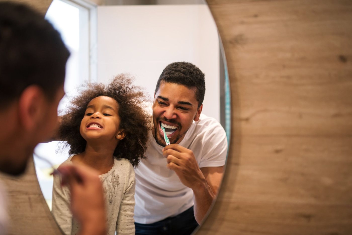 A parent and child brushing their teeth together